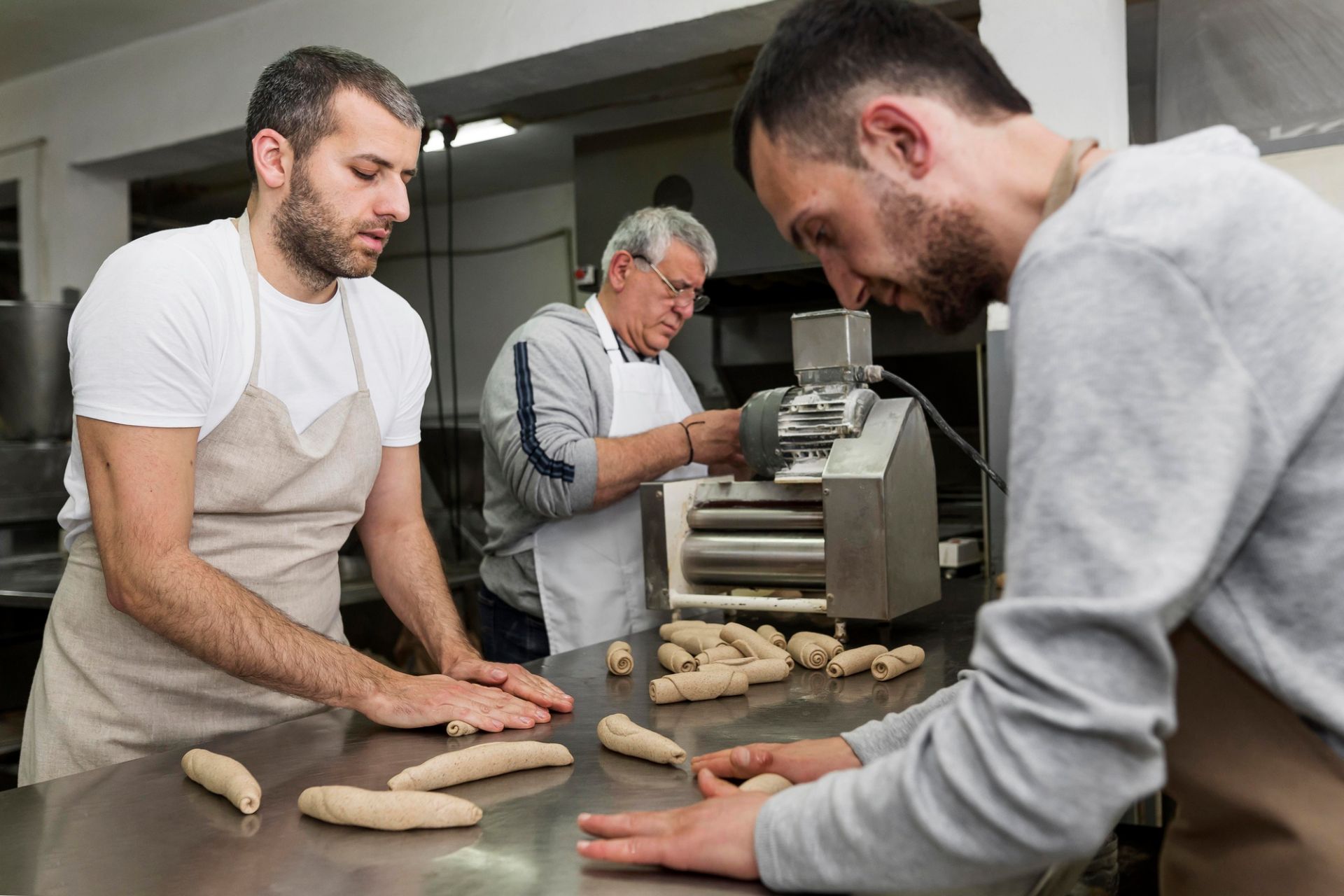 3 bakers rolling dough to make bread