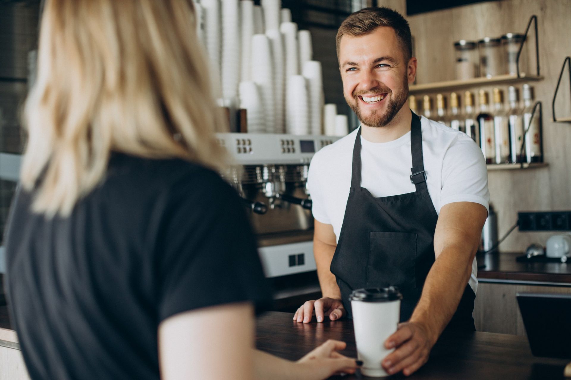 Barista smiling and handing a customer a coffee